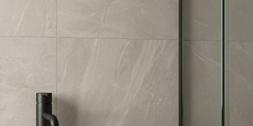 Close-up of 600x1200mm warm greige porcelain wall tiles with subtle veining and minimal grout lines in a modern shower.